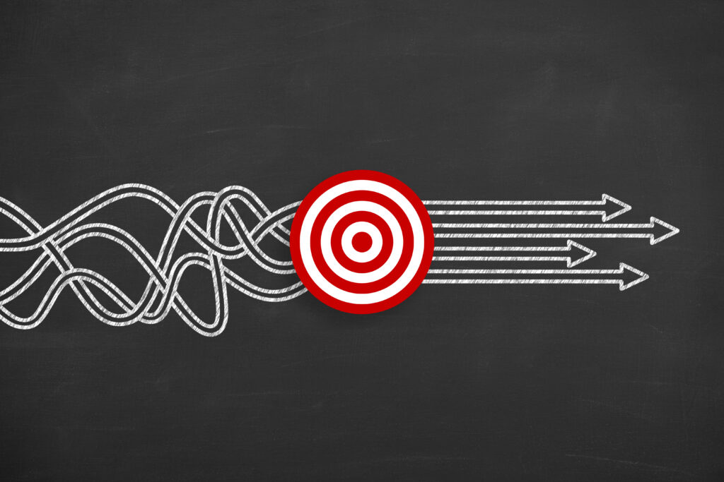 A tangled white chalk line on a blackboard straightens into multiple arrows as it passes through a red target symbol.
