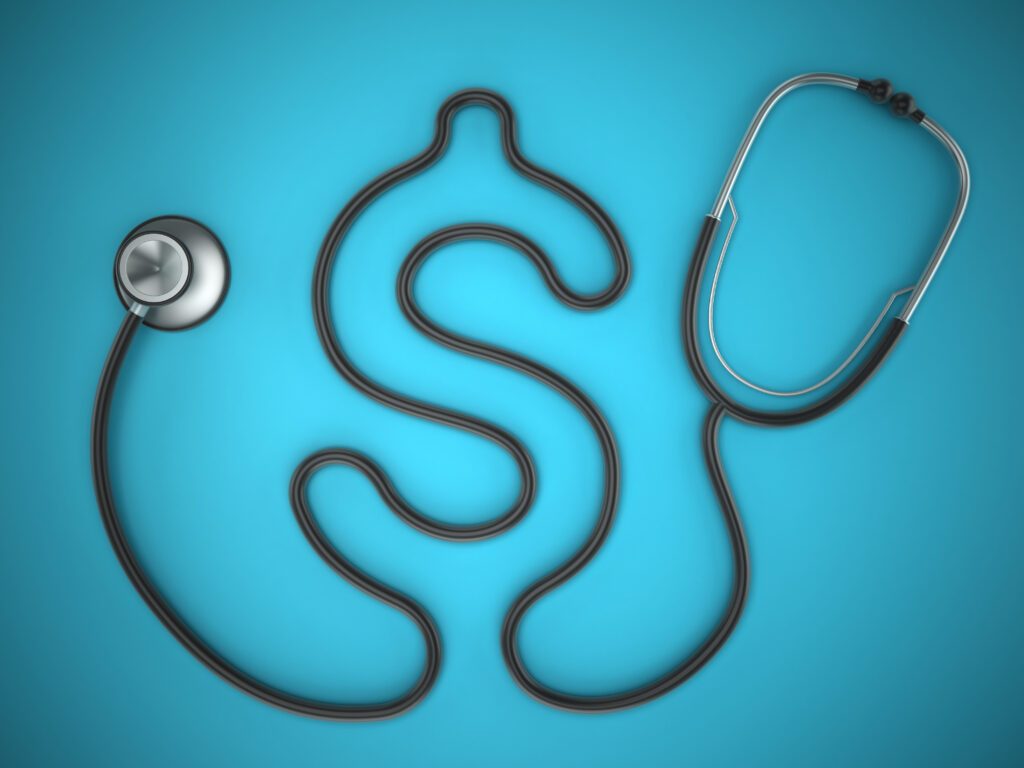 A stethoscope shaped like a dollar sign is placed on a blue background, symbolizing the relationship between healthcare and financial costs.